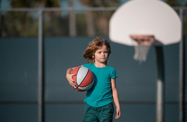 Kleines kaukasisches Sportkind spielt Basketball und hält den Ball