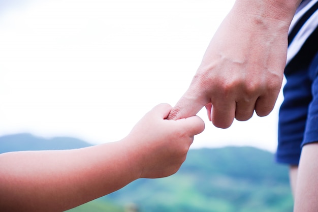 Kleines Kind, das Hand einer Mutter hält.