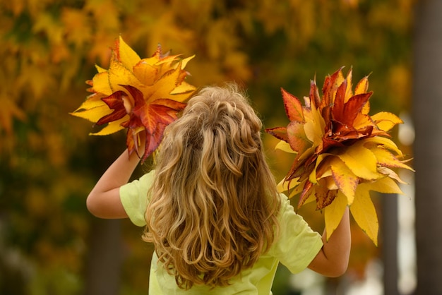 Kleines Kind, das im Herbst auf dem Naturspaziergang im Freien spielt, für fröhlichen Herbst, lustigen Herbst