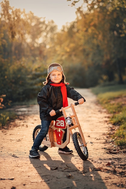 Kleines Kind, das im Herbst ein Laufrad in Oberbekleidung fährt