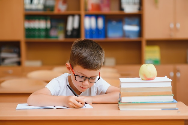 Kleines Kind, das mit bunten Bleistiften drinnen schreibt. Grundschule und Bildung. Kind, das das Schreiben von Buchstaben und Zahlen lernt.