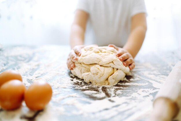 Kleines Kind, das Teig zum Backen zubereitet. Kleine Hände kneten Teig und gerollten Teig