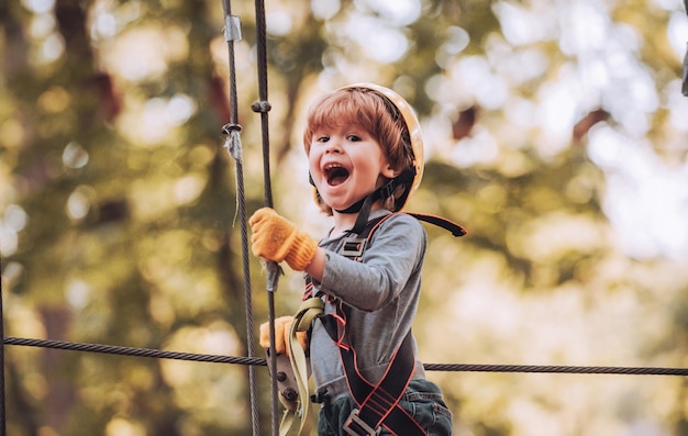 Kleines Kind klettert im Abenteuer-Aktivitätspark mit Helm und Sicherheitsausrüstung Kleinkinder klettern i