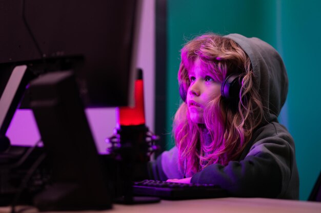 Kleines Kind mit Desktop-PC bei Nacht Kind Junge beleuchtet durch das blaue Licht eines Computerbildschirms Gamer spielen Computerspiele Neonbeleuchtung