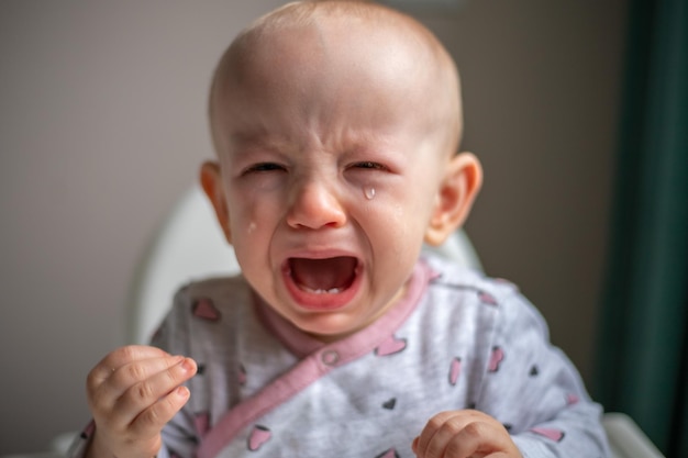 Kleines Kind mit Tränen in den Augen weint laut mit weit geöffnetem Mund