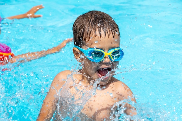 Kleines Kind schwimmt im Pool, spielt Spritzwasser