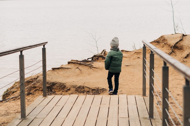 Kleines Kind sitzt am Ufer des Sees und spielt mit Wasser glücklicher Kinderjunge, der spielt und hat