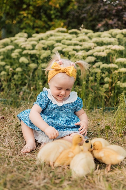 Foto kleines kind sitzt im gras neben den entenküken