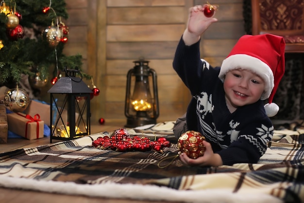 Kleines Kind sitzt vor einem Weihnachtsbaum und spielt mit Spielzeug