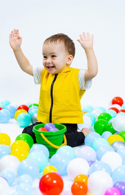 Kleines Kind spielt mit bunten Bällen. Verspielter Junge, der Spaß auf dem Spielplatz hat