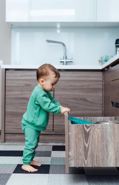 Kleines Kind spielt mit Schublade Baby allein in der Küche Babysicherheit in der Küche