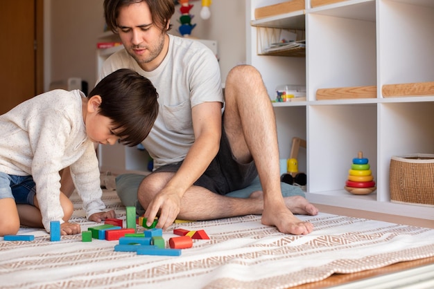 Kleines Kind und sein Vater spielen zu Hause mit Holzbausteinen. Häuslicher Unterricht. Bleib zuhause. Familienzeit