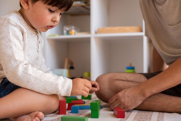 Kleines Kind und sein Vater spielen zu Hause mit Holzbausteinen. Häuslicher Unterricht. Bleib zuhause. Familienzeit