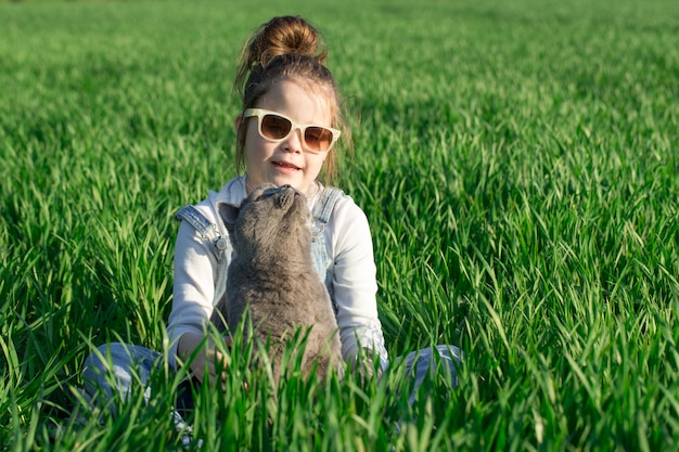 Kleines Kindermädchen, das Spaß mit Katze am Garten hat