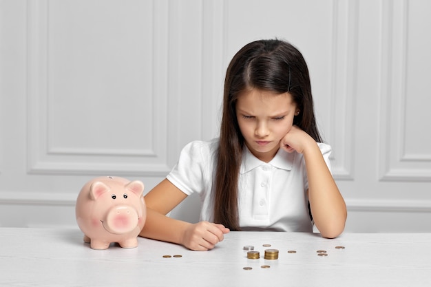 Kleines Kindermädchen mit Sparschwein zu Hause