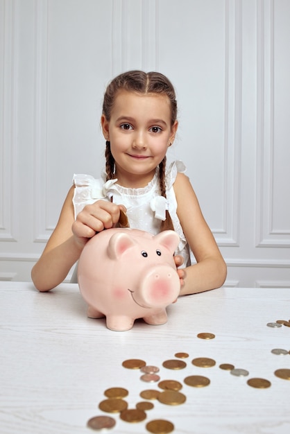 Kleines Kindermädchen mit Sparschwein zu Hause