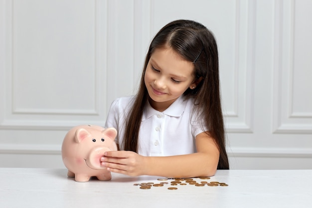 Kleines Kindermädchen mit Sparschwein zu Hause