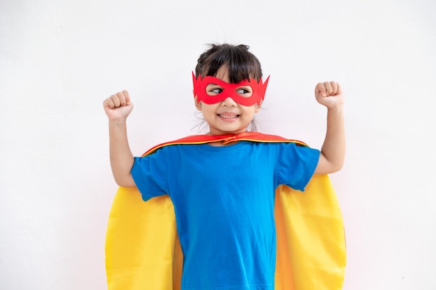 Kleines Kindermädchen spielt Superhelden. Kind auf dem weißen Hintergrund. Girl-Power-Konzept