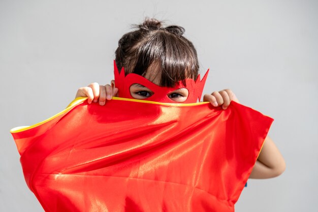 Kleines kindermädchen spielt superhelden. kind auf dem weißen hintergrund. girl-power-konzept