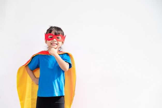 Kleines Kindermädchen spielt Superhelden. Kind auf dem weißen Hintergrund. Girl-Power-Konzept