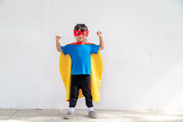 Kleines Kindermädchen spielt Superhelden. Kind auf dem weißen Hintergrund. Girl-Power-Konzept