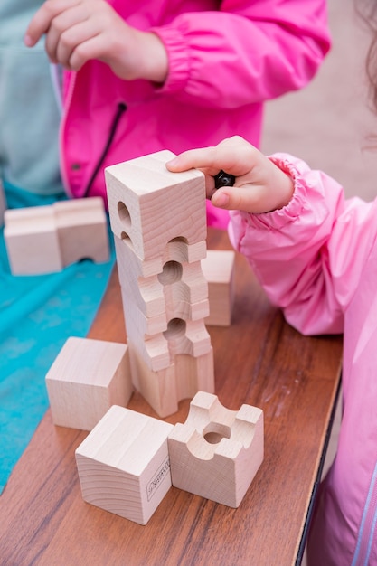 Kleines Kleinkind spielt mit einem Holzkonstruktor Vorschulkind, das zu Hause lernt, Mosaik zu machen Frühe Entwicklung Spielen und LernenKinderhände sammeln Konstruktorwürfel-Aktivitätskonzept