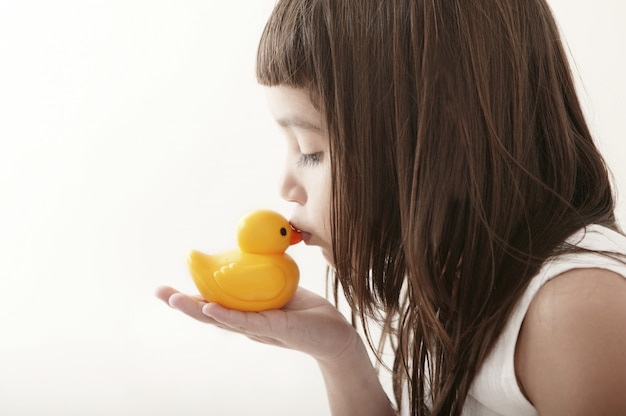 Kleines kleinkindmädchen, das eine gelbe badente küsst