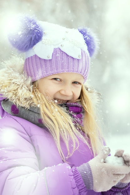 Kleines lächelndes Mädchen draußen zur Schneefallzeit