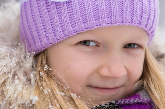 Kleines lächelndes Mädchen draußen zur Schneefallzeit