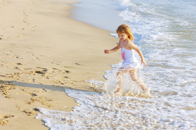 Kleines Mädchen am Strand läuft im Wasser