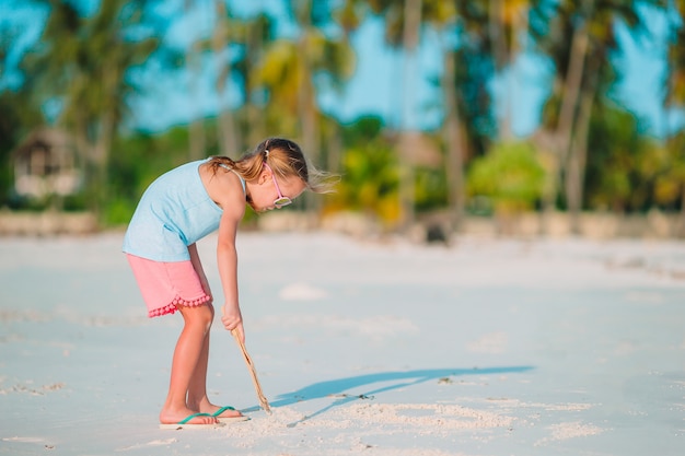 Kleines Mädchen am tropischen weißen Strand, der Sandburg macht