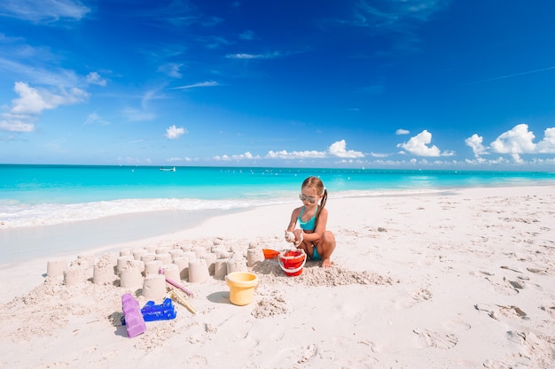 Kleines Mädchen am tropischen weißen Strand, der Sandburg macht