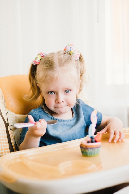 Kleines Mädchen an ihrem Geburtstag nimmt Glückwünsche entgegen und isst Kuchen