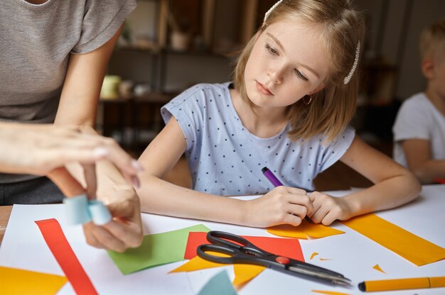 Kleines Mädchen arbeitet mit farbigem Papier in der Werkstatt