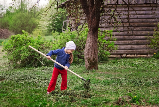 Kleines Mädchen auf dem Land mit einem Rechen