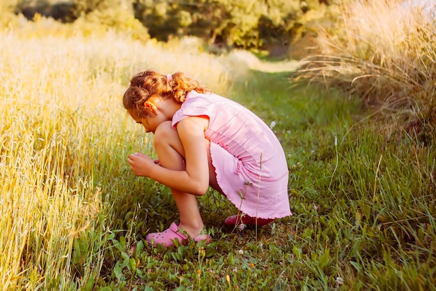 Kleines Mädchen auf einem Sommerfeld an einem warmen sonnigen Tag