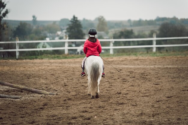 Kleines Mädchen auf einem weißen Pony