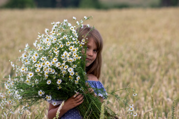 Kleines Mädchen auf einem Weizenfeld mit Kamillenblüten.