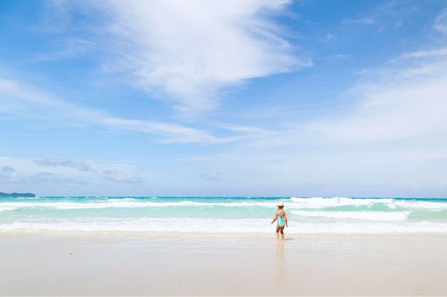 Kleines Mädchen badet im Meer am Strand mit weißem Sand