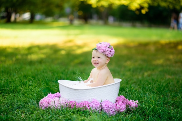 Kleines Mädchen badet in einem Milchbad im Park. Das Mädchen hat Spaß im Sommer.