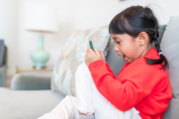 Kleines Mädchen benutzt zu Hause ein Handy