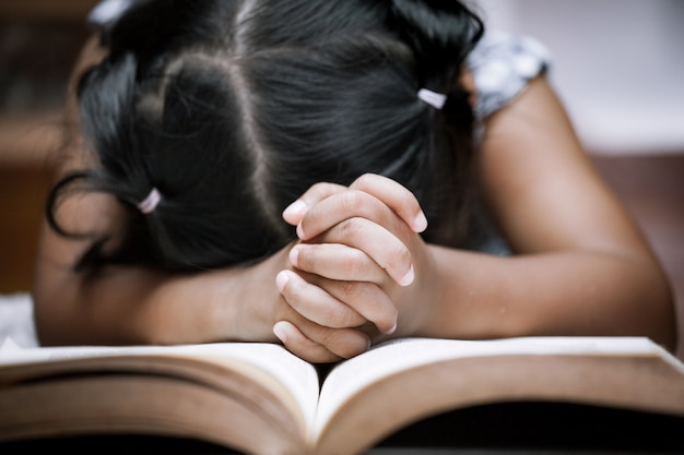 Kleines Mädchen betet mit einer heiligen Bibel