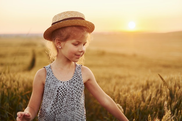 Kleines Mädchen, das abends auf dem landwirtschaftlichen Feld steht Konzeption der Sommerfreizeit