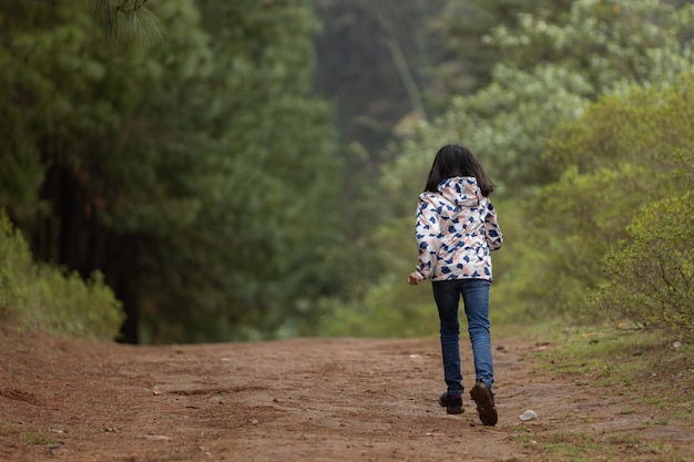 Kleines Mädchen, das allein im Wald läuft