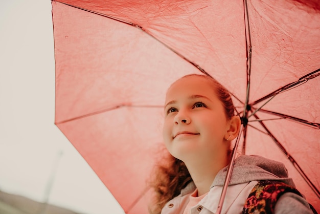 Kleines Mädchen, das am Regentag auf den Bus wartet