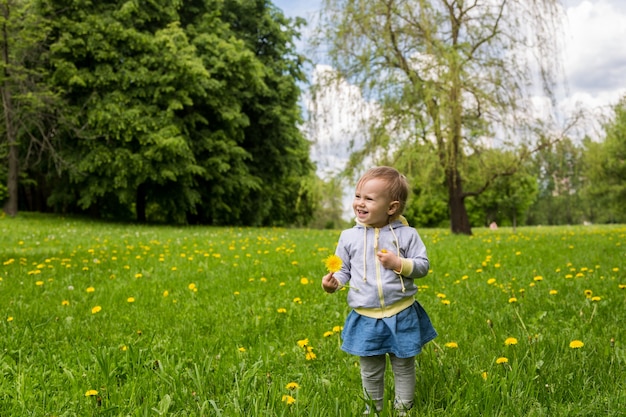 Kleines Mädchen, das auf dem grünen Gras steht