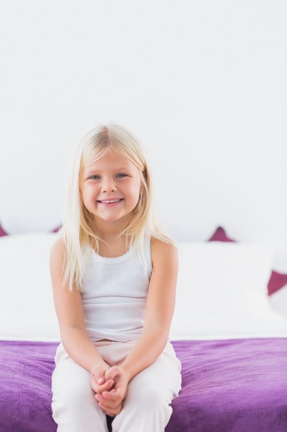 Kleines Mädchen, das auf einem Doppelbett sitzt