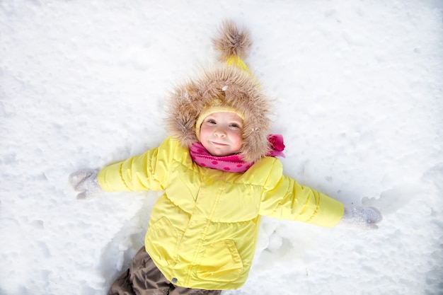 Kleines Mädchen, das auf Schnee liegt