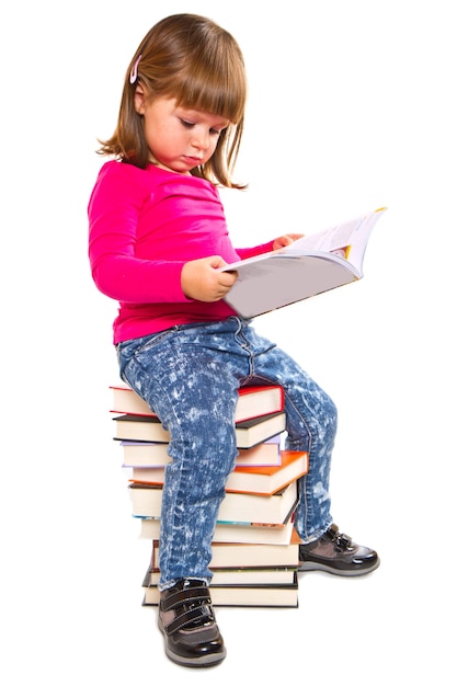 Kleines Mädchen, das auf Stapel Büchern sitzt
