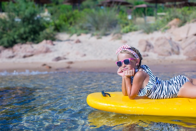 Kleines Mädchen, das das Schwimmen im gelben Kajak im klaren Türkiswasser genießt